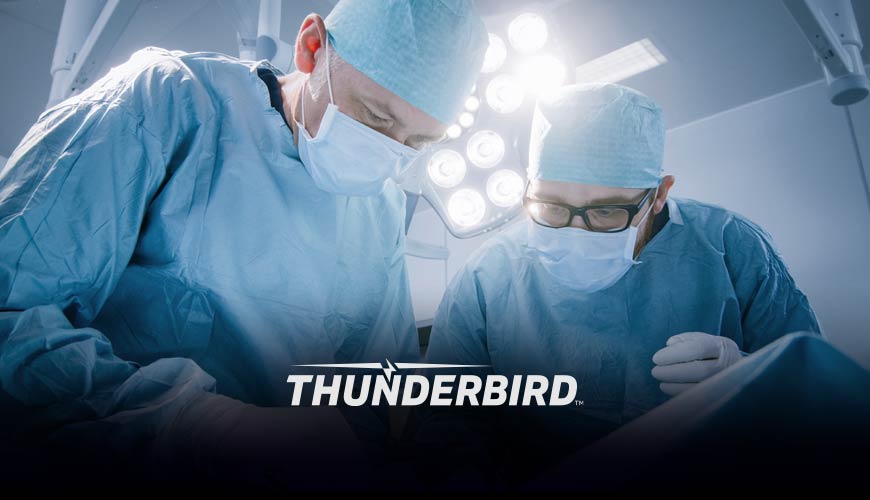 Two surgeons in operating room. Thunderbird Logo overlay