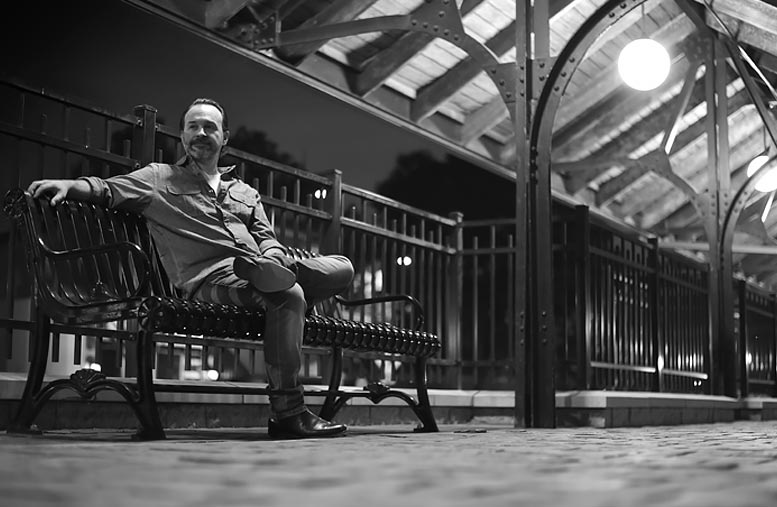 Brian Moore sitting on bench at the train station.