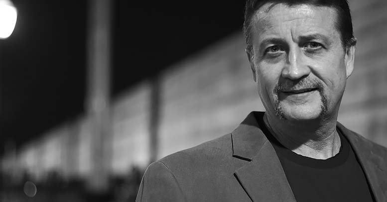 Ken Jackson in front of railroad tracks looking at camera.